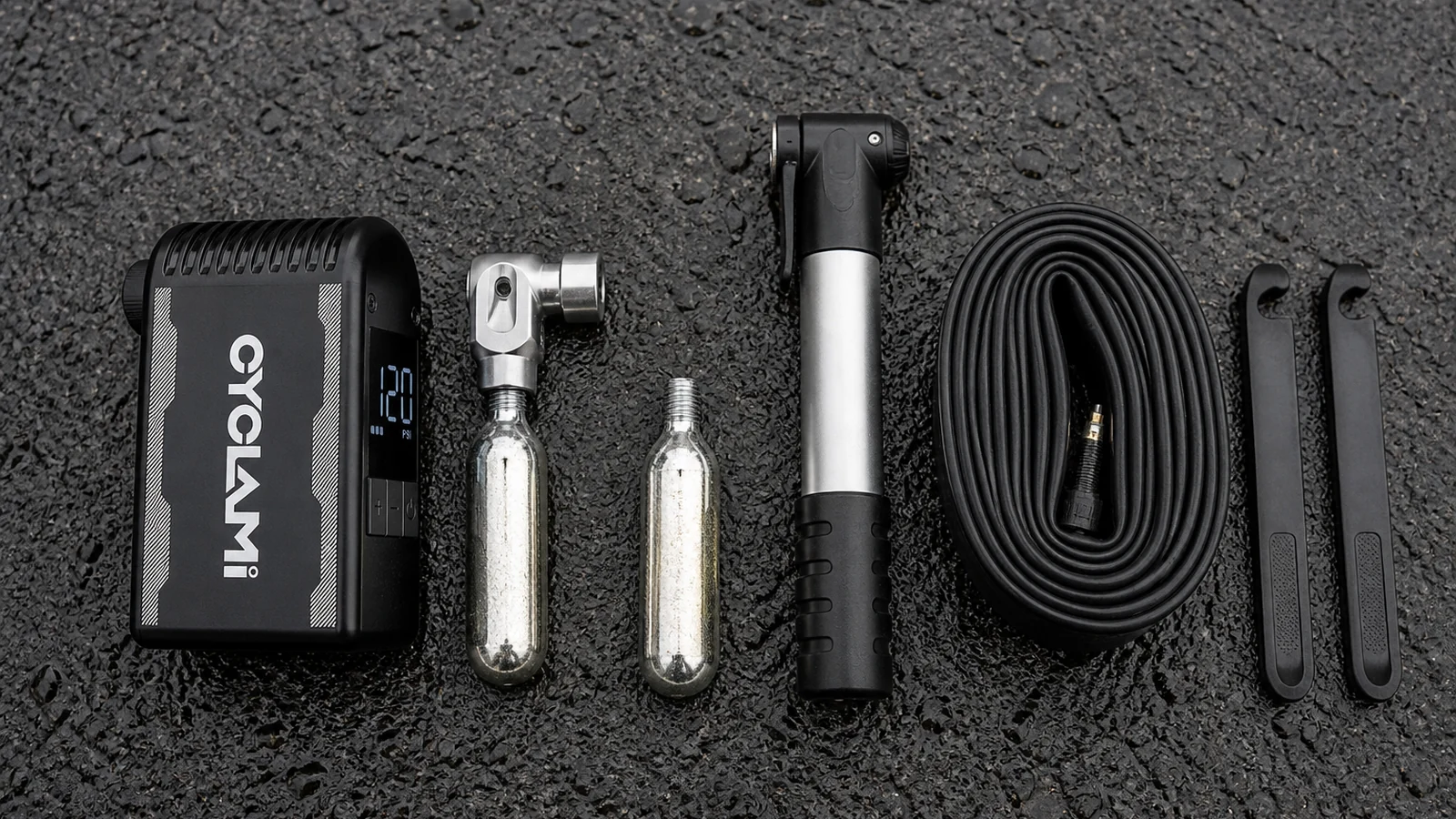 Electric inflator, CO2 inflator head, silver cartridges, floor pump and tyre levers beside a bicycle wheel